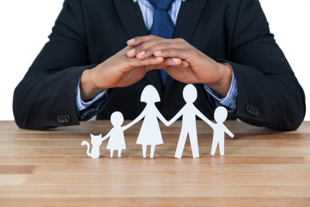 businessman protecting paper cut out family