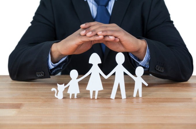 businessman protecting paper cut out family